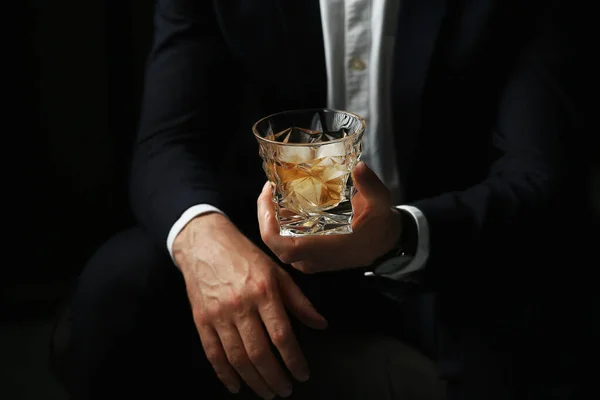 黒の背景に氷のキューブとウィスキーのグラスを持っている男 クローズアップ — ストック写真