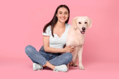 Pembe arka planda şirin Labrador Retriever köpeği olan mutlu bir kadın. Sevimli hayvan.