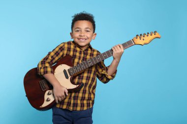 Turkuaz arka planda elektro gitarı olan sevimli Afro-Amerikalı çocuk.