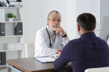 Klinikteki ahşap masada kıdemli doktora danışmanlık yapıyorum.