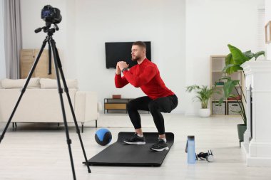 Trainer recording workout on camera at home