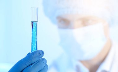Genetik araştırma. Bilim adamlarının elinde sıvı ve DNA yapısının resmedildiği test tüpü var.
