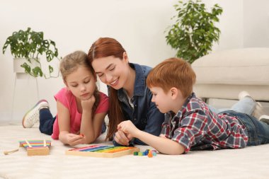 Mutlu anne ve çocuklar odada farklı matematik oyun setleriyle oynuyorlar. Matematiği zevkle çalış