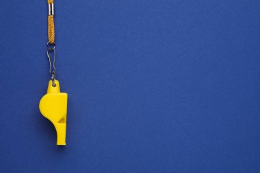 Mavi arka planda kablosu olan sarı bir düdük. Metin için boşluk