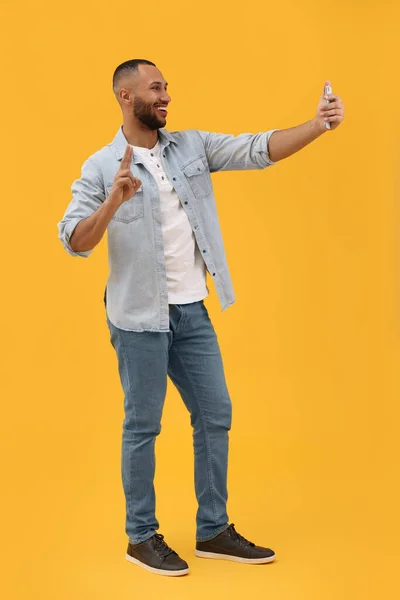 Uśmiechnięty Młody Człowiek Robi Sobie Selfie Smartfonem Pokazuje Znak Pokoju — Zdjęcie stockowe