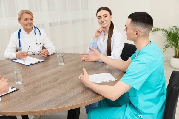 医学会議だ 診療所の木製のテーブルで議論している医師のチーム — ストック写真