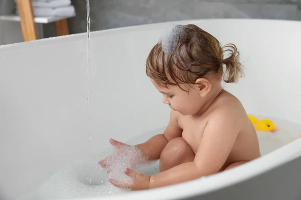 Cute little girl taking bubble bath indoors. Space for text