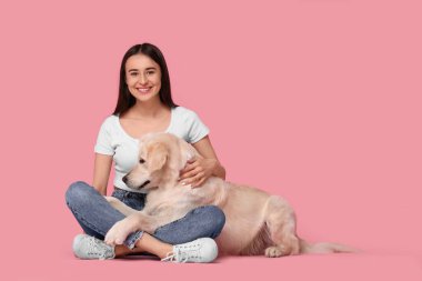 Pembe arka planda şirin Labrador Retriever köpeği olan mutlu bir kadın. Mesaj için yer var. Sevimli hayvan.