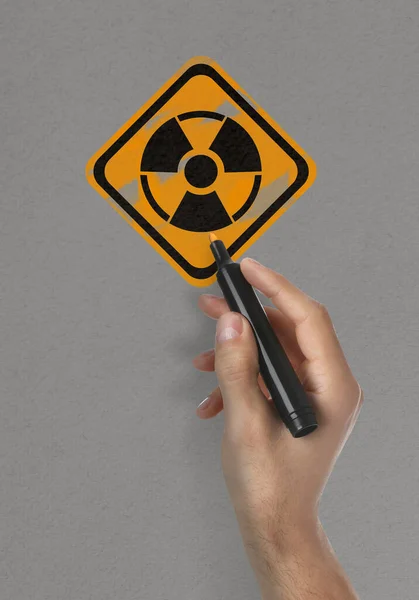 Hombre Pintando Símbolo Advertencia Radiación Con Marcador Superficie Gris Claro —  Fotos de Stock