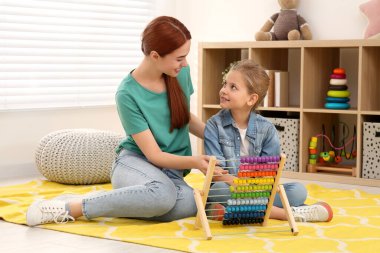 Mutlu anne ve kız odada abaküs ile oynuyor. Matematiği eğlenerek öğreniyorum.