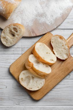 Fresh crispy ciabattas on white wooden table, flat lay