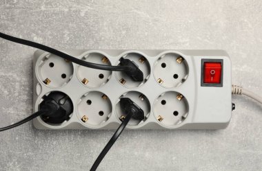 Açık gri masada uzantı kablosu olan güç şeridi, üst manzara. Elektrikçi ekipmanı.