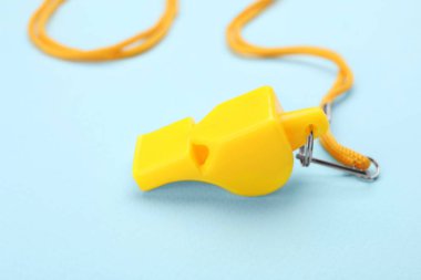 Açık mavi arka planda kablosu olan sarı bir ıslık, yakın plan.