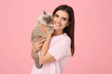 Pembe arka planda kedisi olan bir kadın.