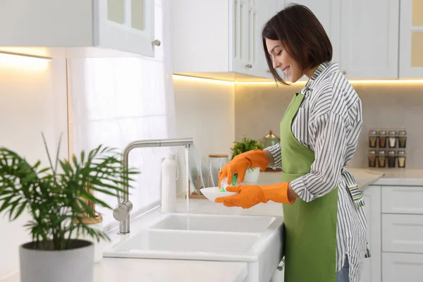 在现代厨房里 快乐的年轻女人正在洗碗 — 图库照片