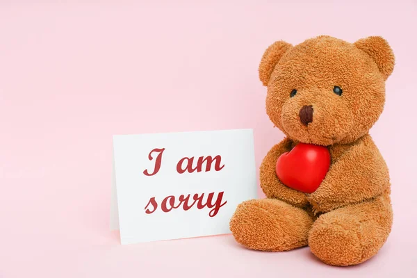 可爱的泰迪熊把红心贴在卡片上 上面写着 对不起 粉红的背景 空白的文字 — 图库照片