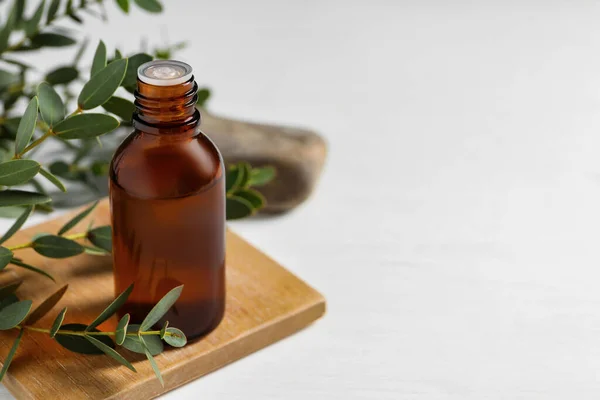 Flasche Ätherisches Eukalyptusöl Und Pflanzenzweige Auf Weißem Tisch Platz Für — Stockfoto