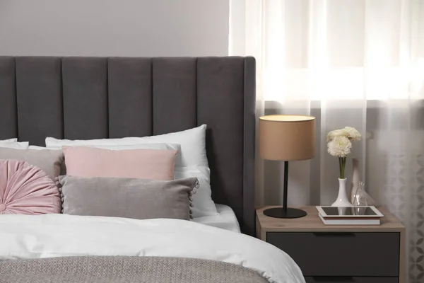 舒适的床 有靠垫 灯和不同的装饰在床头柜的房间里 别致的内饰 — 图库照片