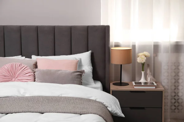 舒适的床 有靠垫 灯和不同的装饰在床头柜的房间里 别致的内饰 — 图库照片