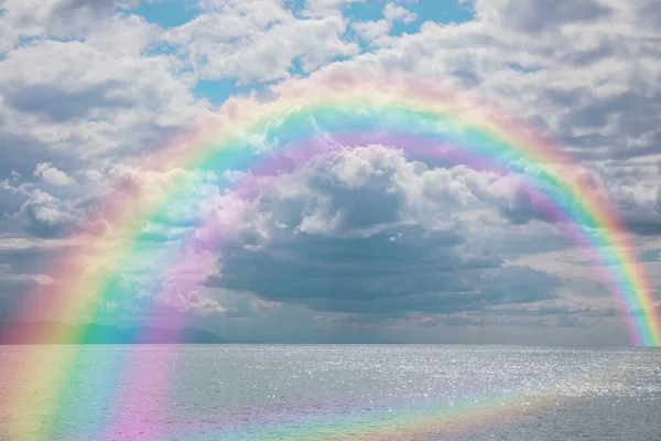 Beautiful seascape with bright rainbow and fluffy clouds