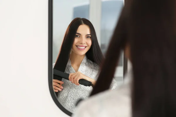 Vacker Lycklig Kvinna Med Hjälp Hår Järn Nära Spegel Inomhus — Stockfoto