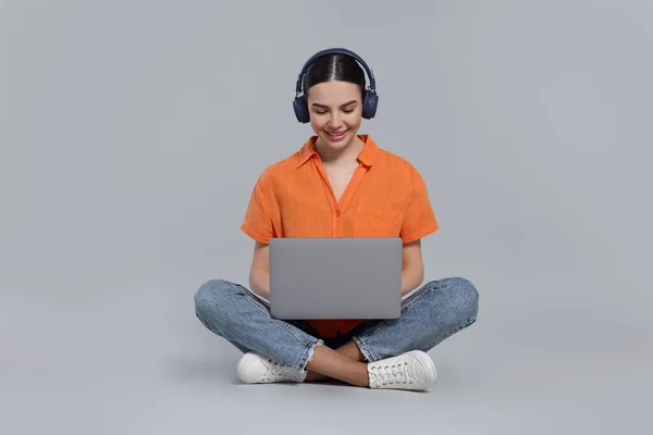 Glückliche Frau Kopfhörer Mit Laptop Auf Hellgrauem Hintergrund — Stockfoto
