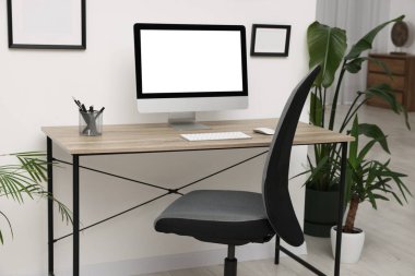 Rahat ofis koltuğu, masa ve ev bitkileriyle süslü bir oda.