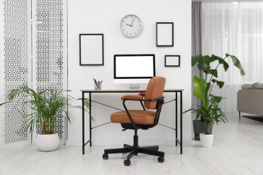 Rahat ofis koltuğu, masa ve ev bitkileriyle süslü bir oda.