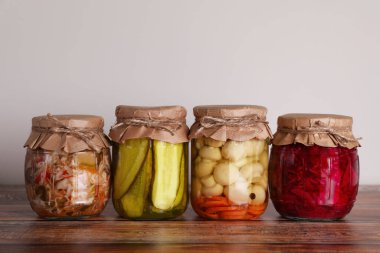 Farklı korunmuş sebzelerle dolu kavanozlar ahşap masada.