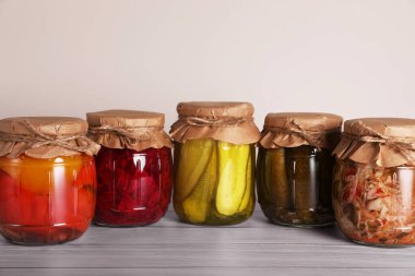Farklı korunmuş sebzelerle dolu kavanozlar ahşap masada.