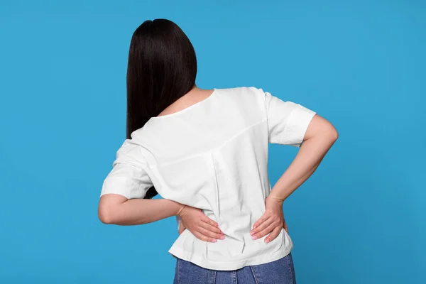 年轻女人背痛 背带浅蓝色背景 关节炎症状 — 图库照片