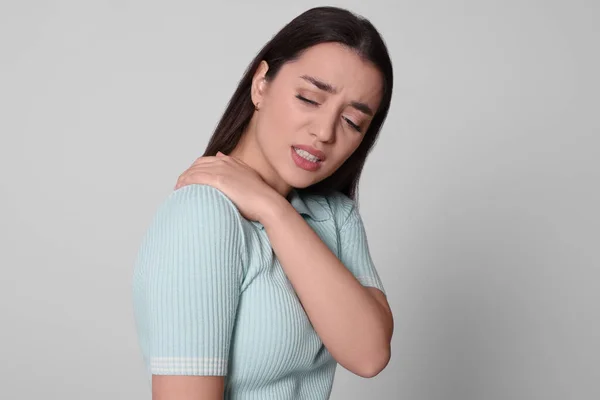 年轻女子肩头疼痛 背景浅灰 关节炎症状 — 图库照片