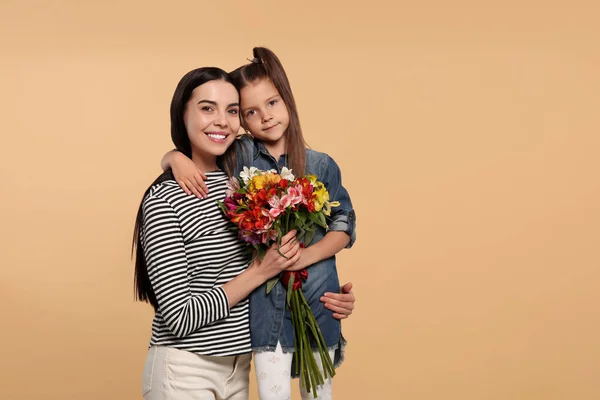 Szczęśliwa Kobieta Jej Uroczą Córką Bukiet Pięknych Kwiatów Beżowym Tle — Zdjęcie stockowe