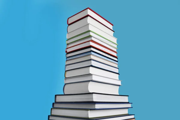 Stack of hardcover books on light blue background