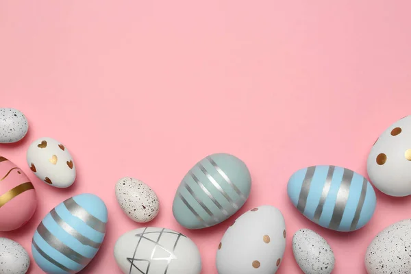 Many painted eggs on pink background, flat lay. Space for text