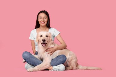 Pembe arka planda şirin Labrador Retriever köpeği olan mutlu bir kadın. Mesaj için yer var. Sevimli hayvan.