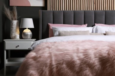 Yastıklı, lambalı ve beyaz komodinli rahat bir yatak. Şık iç mekan