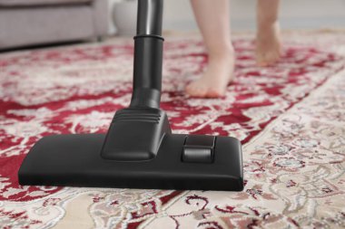 Halıyı elektrikli süpürgeyle temizleyen kadın, yakın çekim.