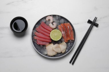 Sashimi seti (çiğ ton balığı, yağlı balık, somon ve karides dilimleri) limon, soya sosu ve buzla servis edilir.