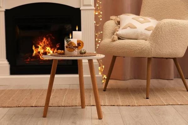 stock image Beautiful burning candles decorated with dry orange slices and cinnamon sticks on white table in room. Christmas atmosphere