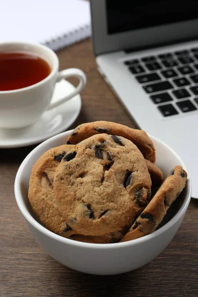 チョコレートチップクッキー 木製テーブルの上の紅茶とラップトップのカップ — ストック写真