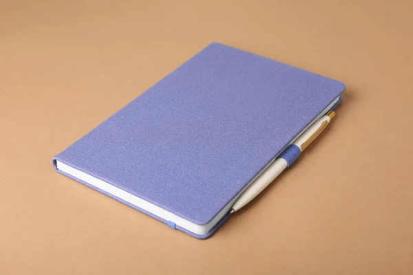 Cuaderno Azul Cerrado Pluma Sobre Fondo Marrón Claro —  Fotos de Stock