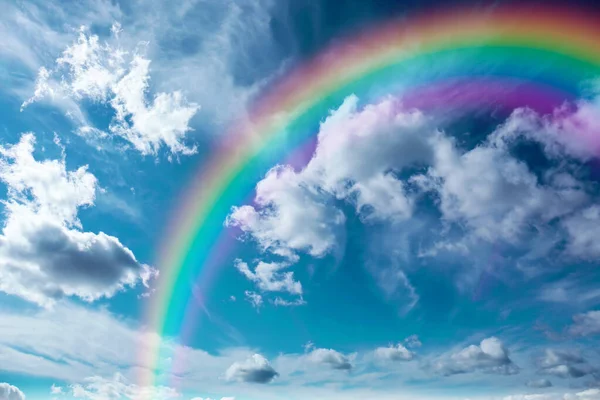 Beautiful sky with bright rainbow and fluffy clouds