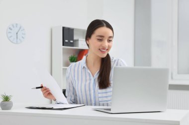 Ofiste dizüstü bilgisayarla çalışan genç bir kadın stajyer.