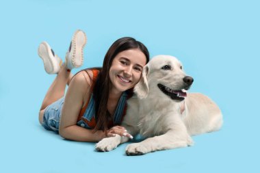 Açık mavi arka planda şirin Labrador Retriever köpeği olan mutlu bir kadın. Sevimli hayvan.