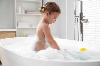 Evde köpüklü banyo yapan tatlı küçük kız.