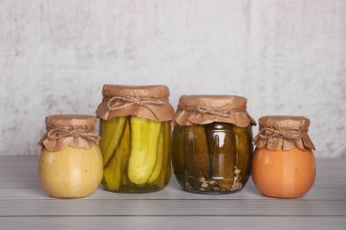 Cam kavanozlar ve ahşap masada farklı korunmuş ürünler.