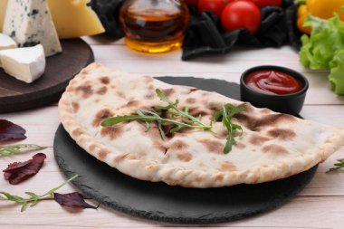 Lezzetli calzone ve hafif ahşap masadaki ürünler, yakın plan.