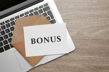 Kahverengi zarf, üzerinde kelime bonusu olan bir mektup ve ahşap masa üzerinde dizüstü bilgisayar, üst manzara. Metin için boşluk