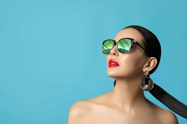 stock image Attractive woman in stylish sunglasses on light blue background. Palm leaves and sky reflecting in lenses. Space for text